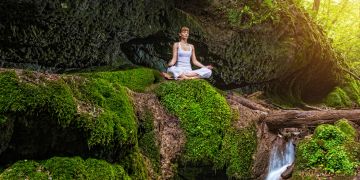 Frau im Lotussitz am Wasserfall in der Natur.