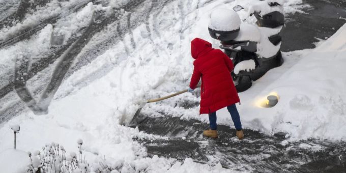 Eine Frau beim Schneeschaufeln in Basel. Schnee