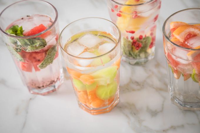 Alles, was hilft, um an heissen Tagen mehr zu trinken: Mit Kräutern, Obst- und Gemüseschnitzen lässt sich Wasser wunderbar aufpeppen. Wasser Glas Obststücke