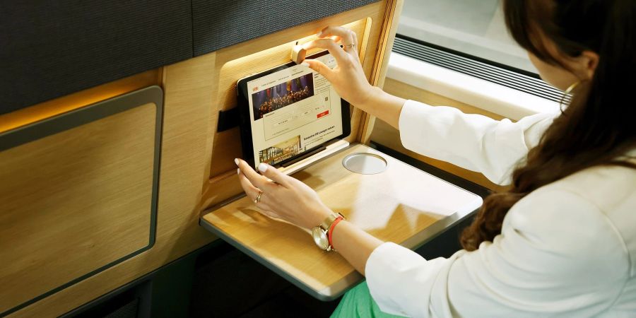 Eine Frau klemmt bei der Präsentation des neuen Designs im ICE in einem Modell ein iPad in eine Halterung für Tablets in den Sitz.