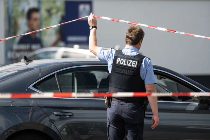 Ein Polizist geht unter dem Absperrband um den Supermarkt in Schwalmstadt (D) hindurch. schwalmstadt