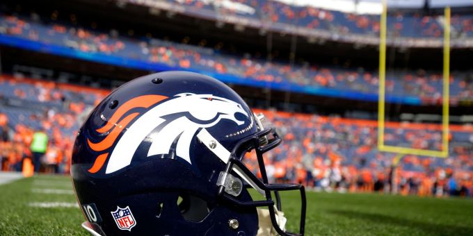 Ein Helm der Denver Broncos liegt vor einem NFL-Footballspiel auf dem Spielfeld. Ein Helm der Denver Broncos liegt vor einem NFL-Footballspiel auf dem Spielfeld.