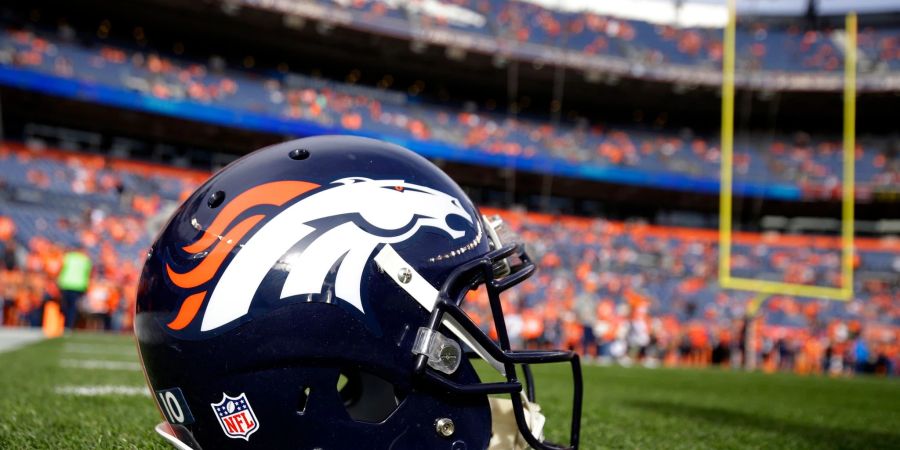 Ein Helm der Denver Broncos liegt vor einem NFL-Footballspiel auf dem Spielfeld.