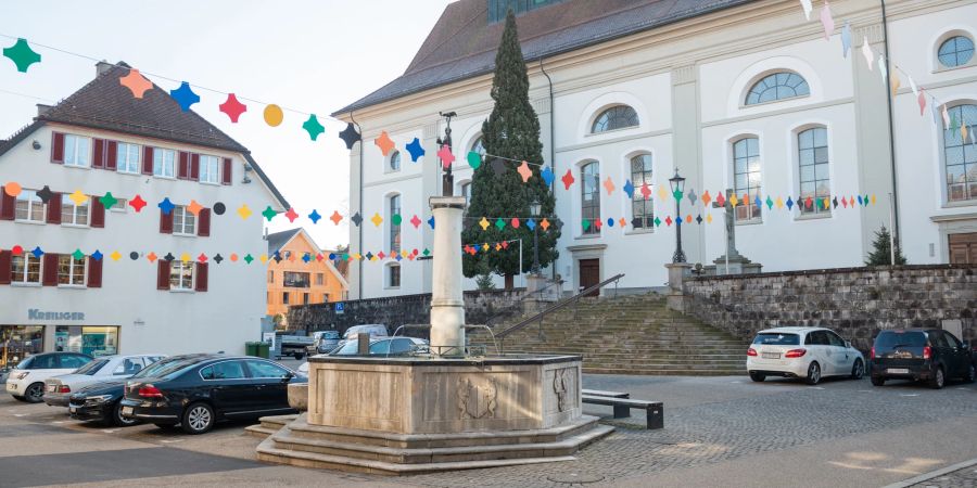 Der Blick auf den Dorfbrunnen und die katholische Pfarrkirche St. Peter und Paul im Zentrum von Willisau.