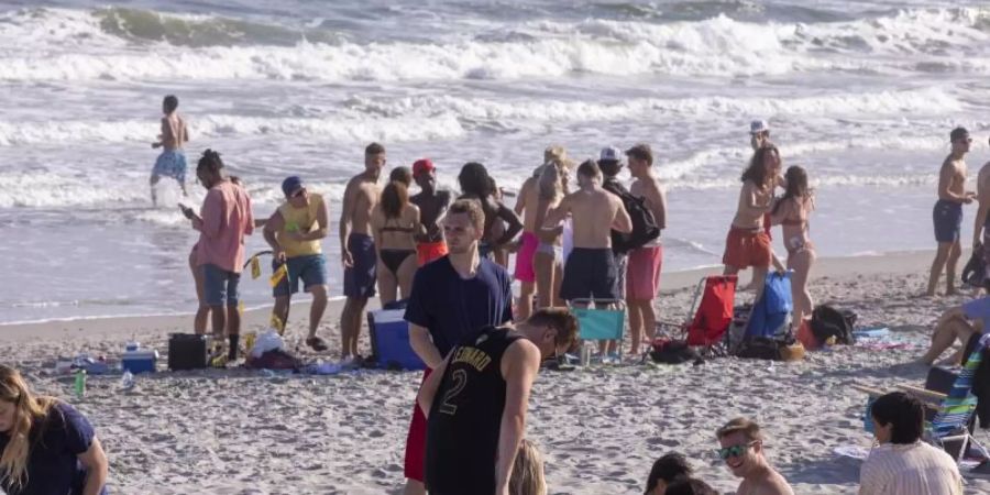 Ungeachtet der Ansteckungsgefahr durch das neuartige Coronavirus vergnügen sich Dutzende Studenten an einem Strand an der US-Ostküste. Foto: Jason Lee/The Sun News/AP/dpa