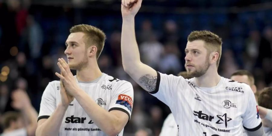 Kiels Nikola Bilyk (l) und Niclas Ekberg feiern den Sieg gegen den HC Erlangen. Foto: Axel Heimken/dpa
