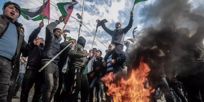 Palästinensische Demonstranten stehen um brennende Autoreifen, halten Flaggen und rufen Parolen während eines Protestes gegen den erwarteten Vorschlag für einen Nahost-Plan durch Trump, Präsident der USA. Nahost-Plan von Trump