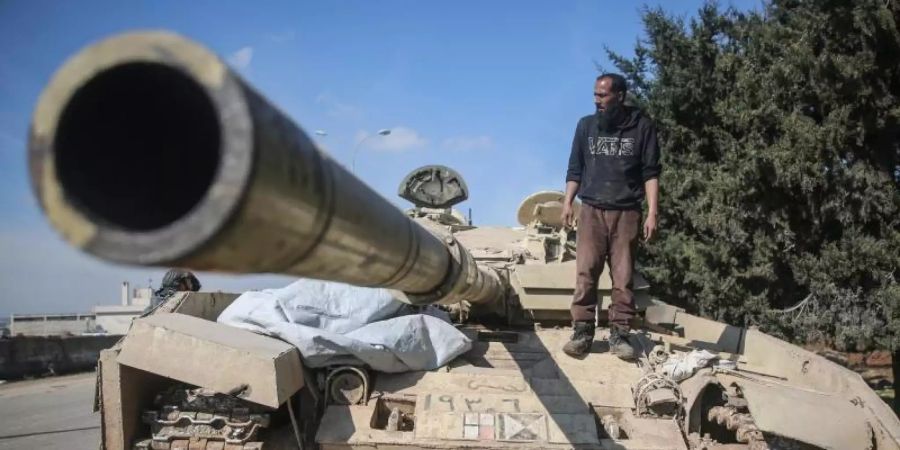 Ein Kämpfer der Nationalen Befreiungsfront (NFL) steht auf einem Panzer der syrischen Regierungstruppen. Foto: Anas Alkharboutli/dpa