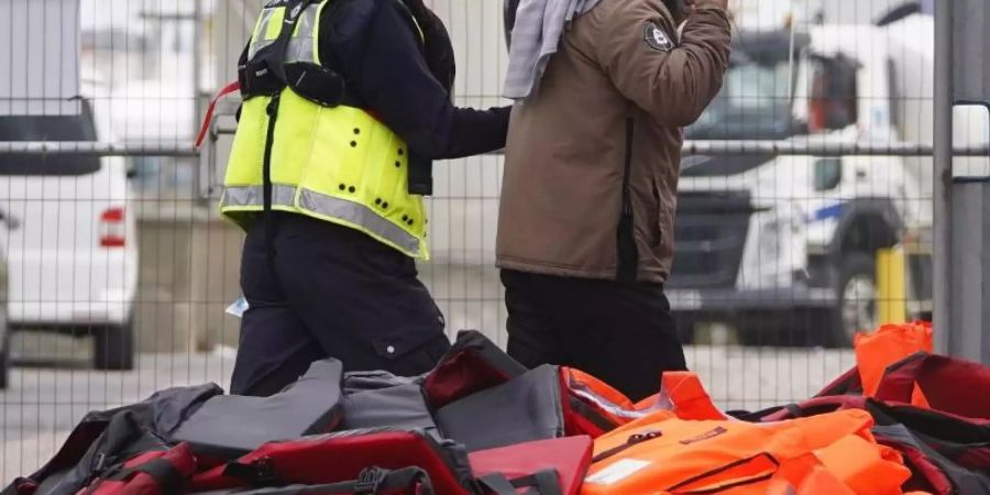 Ein Flüchtling wird von Beamten der Grenzpolizei nach Dover in Kent gebracht. Foto: Gareth Fuller/PA/dpa