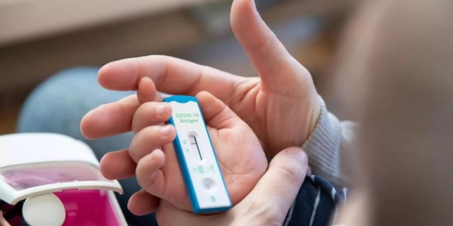 Ein Kita-Kind und seine Mutter warten daheim auf das Ergebnis eines Corona-Selbsttests. Foto: Friso Gentsch/dpa