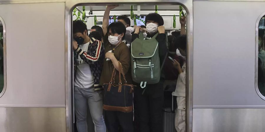 Pendler drängen sich in Tokio in einen Zugwaggon, nachdem ein starkes Erdbeben in der Nacht zum Donnerstag (Ortszeit) die Region Tokio erschüttert und Züge und U-Bahnen vorübergehend lahmgelegt hat. Bei dem Erdbeben sind laut Berichten japanischer Medien mindestens 32 Menschen verletzt worden. Foto: Kiichiro Sato/AP/dpa