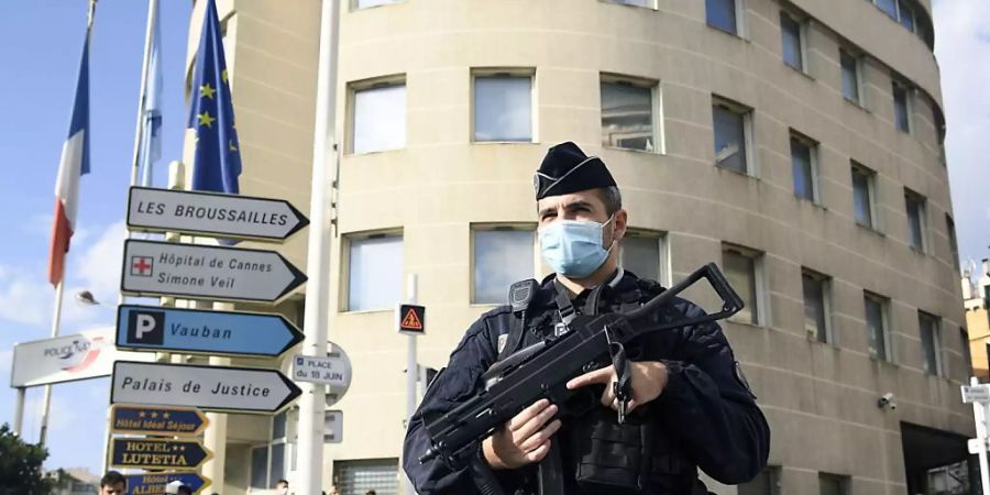 Ein bewaffneter Polizist vor einer Polizeiwache auf einer Strasse. Sicherheitskräfte haben nun zwei Menschen aus dem Umfeld des Täters festgenommen. Foto: Nicolas Tucat/AFP/dpa