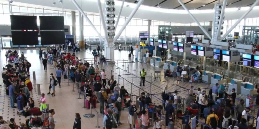 Reisende stehen am Flughafen in Kapstadt in langen Schlangen an den wenigen Schaltern an, die überhaupt noch offen sind. Foto: Kristin Palitza/dpa