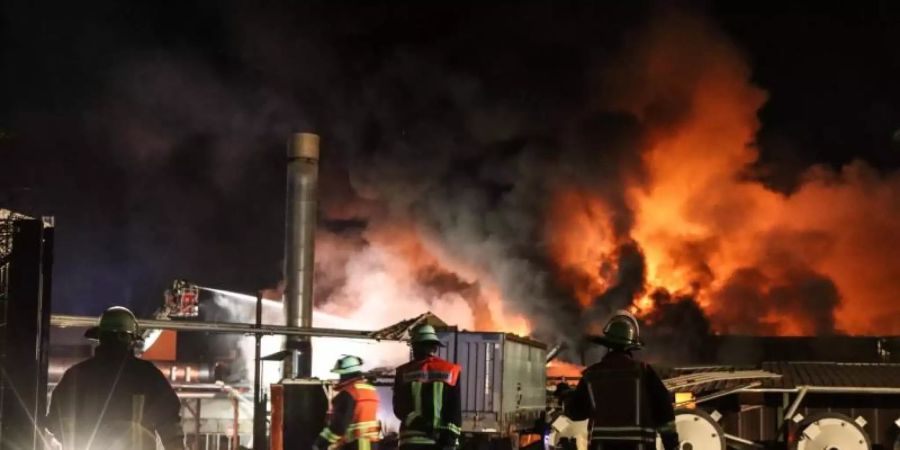 Feuerwehrleute löschen den Brand in einer Tapetenfabrik. Foto: Nadine Weigel/dpa