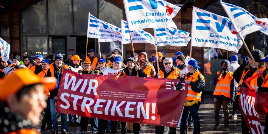 Demonstranten der Eisenbahn- und Verkehrsgewerkschaft (EVG) stehen mit Plakaten vor dem Hauptbahnhof Bremen.