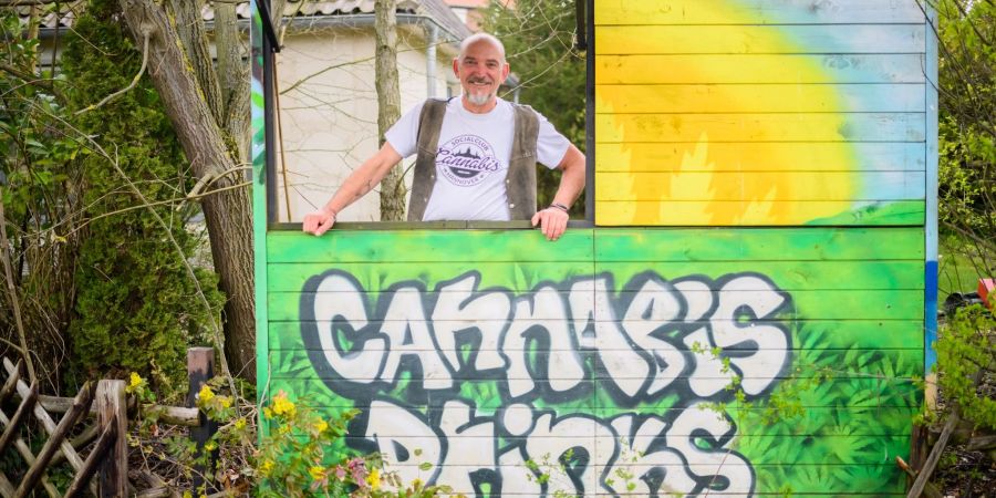 Heinrich Wieker vom Cannabis Socialclub Hannover e.V. an seinem Gartenzaun an einer Bretterbude.