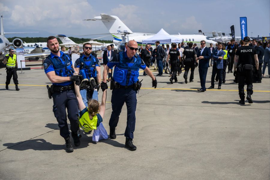 Polizisten führen am Flughafen Genf einen Klimaaktivisten ab.