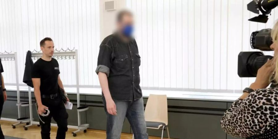 Justizmitarbeiter führen den 39-Jährigen in den Saal des Rostocker Landgerichts. Foto: Bernd Wüstneck/dpa-Zentralbild/dpa