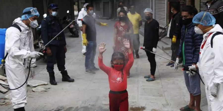 Ein Mädchen in Nepal wird mit Desinfektionsmittel besprüht. Foto: Niranjan Shrestha/AP/dpa