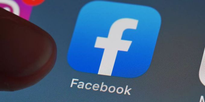 Eine Person zeigt auf einem Tablet auf die Facebook App. Facebook