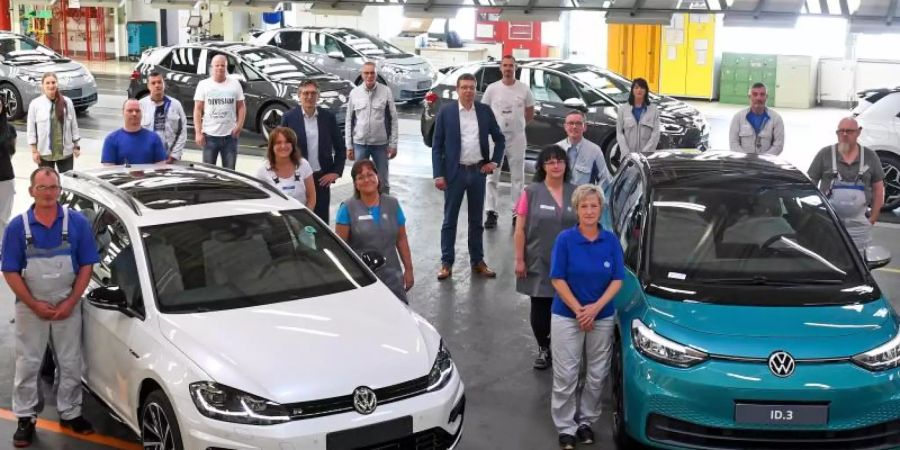 Mitarbeiter des VW-Werks in Zwickau posieren neben einem Golf Variant (l) und einem ID.3. Foto: Hendrik Schmidt/dpa-Zentralbild/dpa