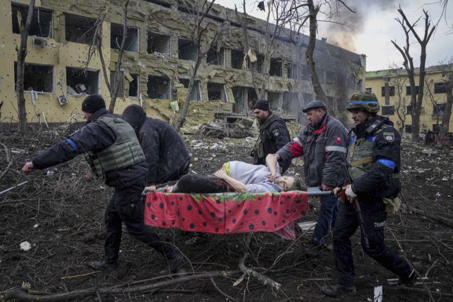 Ukrainische Rettungskräfte und Freiwillige tragen eine verletzte schwangere Frau aus dem durch Beschuss beschädigten Entbindungskrankenhaus in Mariupol, Ukraine, Mittwoch, 9. März 2022.