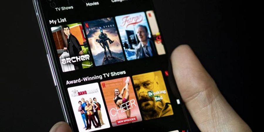 Auf dem Bildschirm eines Smartphones sieht man in der App von Netflix das Filmangebot des Streaminganbieters. Foto: Fabian Sommer/dpa