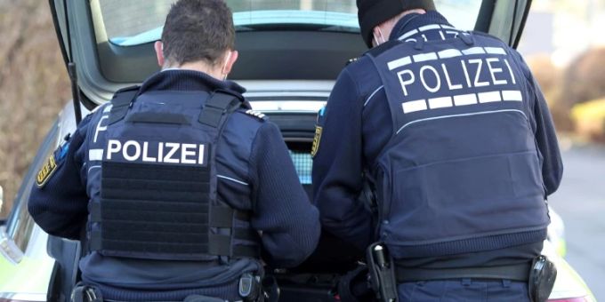 Zwei Polizisten am Kofferraum eines Autos Zwei Polizisten am Kofferraum eines Autos