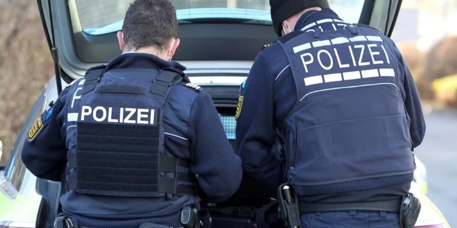Zwei Polizisten am Kofferraum eines Autos