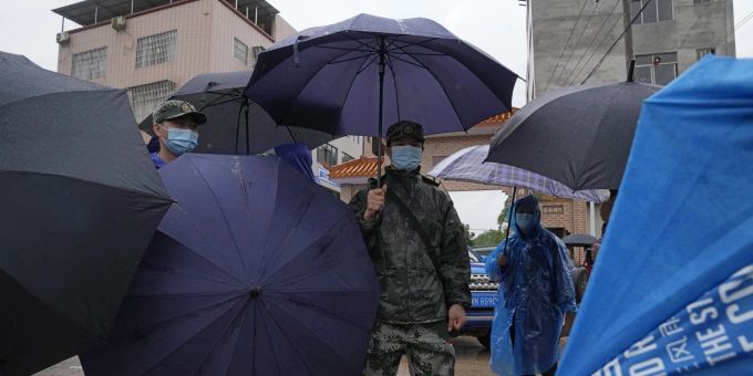 Ein chinesischer Sicherheitsbeamter steht mit Verwandten der mutmasslichen Opfer im Regen. Wegen der schlechten Wetterverhältnisse musste die Suchaktion heute zwischenzeitlich unterbrochen werden. China Plane Crash