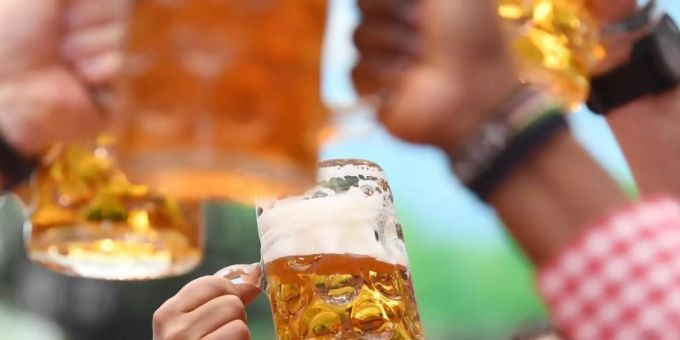 Besucher prosten sich in einem Bierzelt mit Biergläsern zu. Foto: Tobias Hase/dpa/Archiv Bier Fest