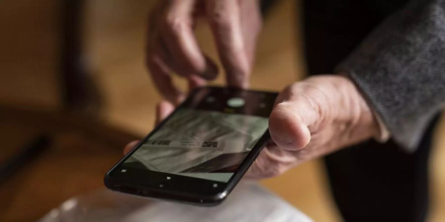 Eine Testperson registriert mit ihrem Smartphone den PCR Covid-19 Test. (Archivbild)