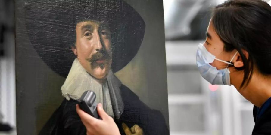 Fuhyi Kuo, Gemälde-Restauratorin der Stiftung Schloss Friedenstein, betrachtet das «Brustbild eines jungen Mannes» von Frans Hals (1582/83-1666). Foto: Martin Schutt/dpa-Zentralbild/dpa