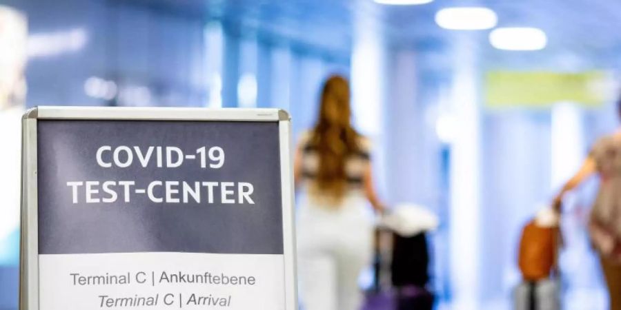 Ein Schild weist Reisende in einem Flughafen auf das Corona-Testzentrum hin. Foto: Moritz Frankenberg/dpa