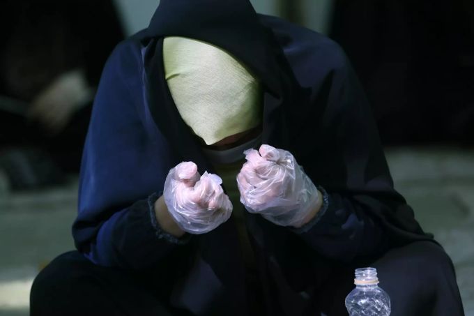 Eine Gläubige trägt eine schützende Gesichtsmaske und Handschuhe. iran