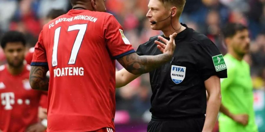 Jérôme Boateng (l) diskutiert mit Schiedsrichter Christian Dingert über dessen Elfmeterentscheidung. Foto: Angelika Warmuth
