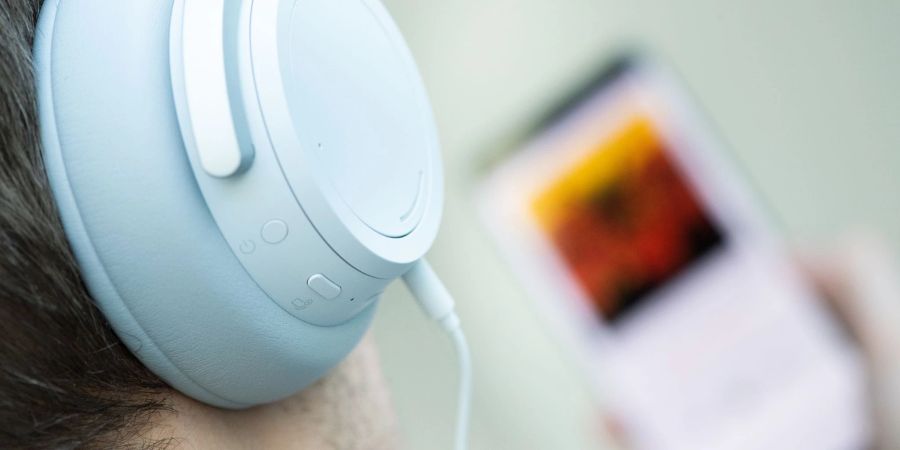 Ein junger Mann hört mit Kopfhörern Musik. Doch Kopfhörer bergen Risiken, vor allem bei Dauerbeschallung in hoher Lautstärke.