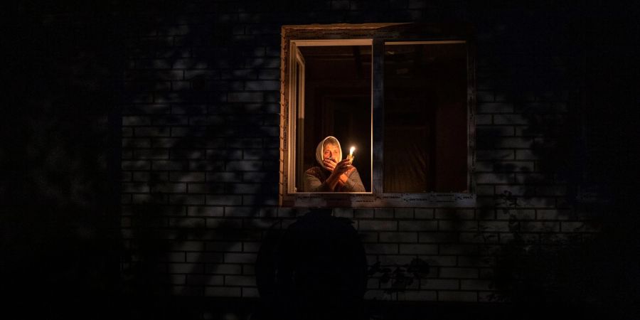 Die 70-Jährige Catherine steht während eines Stromausfalls in Borodjanka mit einer Kerze am Fenster.