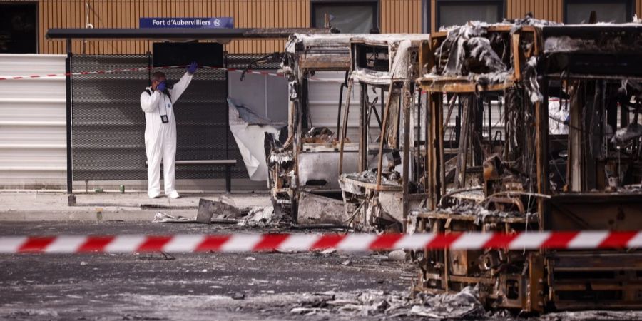 Polizei neben ausgebrannten Bussen