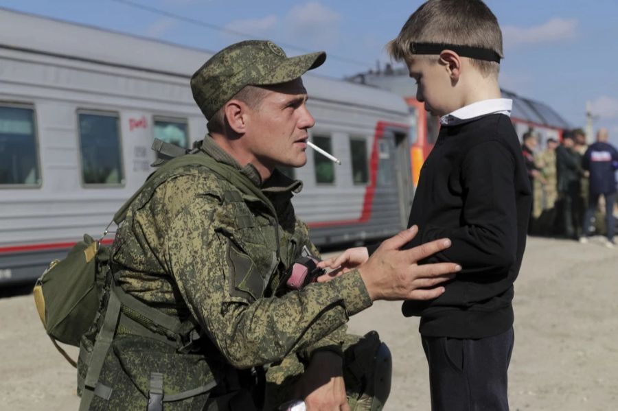 Ein russischer Rekrut spricht mit seinem Sohn, bevor er einen Zug am Bahnhof in Prudboi, Region Wolgograd, Russland, nimmt, Donnerstag, 29. September 2022.