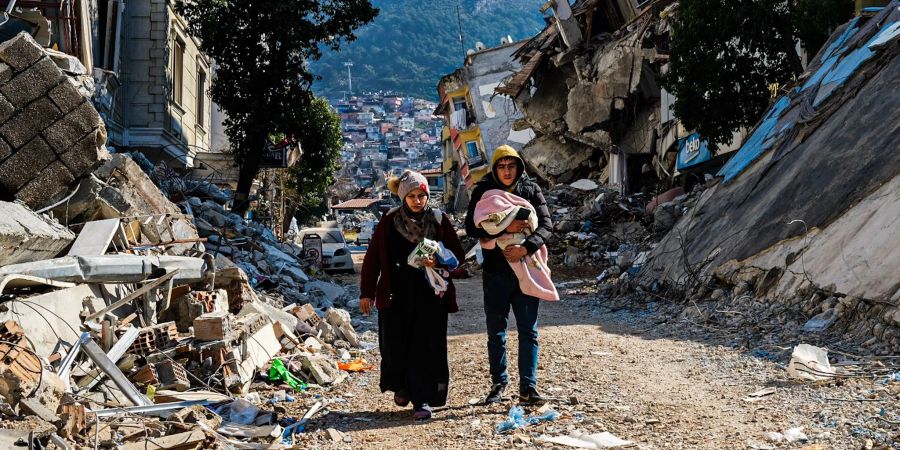 Eine Frau und ein junger Mann gehen durch die Trümmer im türkischen Hatay.