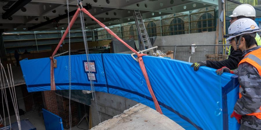 Mitarbeiter einer Spezialfirma transportieren auf der Baustelle des Meeresmuseums eine über sechs Meter lange Acrylglasscheibe aus Japan.