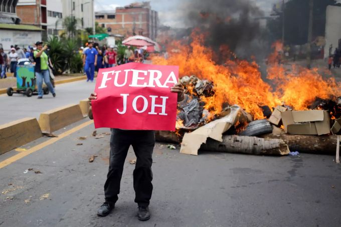 Ein Demonstrant hält ein Schild mit der Aufschrift «Fuera JOH» (Juan Orlando Hernández raus) in Honduras Hauptstadt Tegucigalpa am 06. August. Foto: Gustavo Amador/EPA Juan Orlando Hernández Honduras