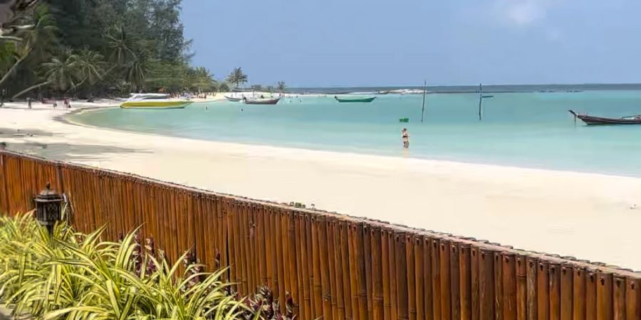 Strand und blaues Meer mit Holzzaun.