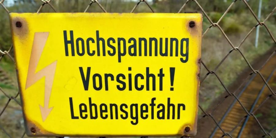 An einer Eisenbahnbrücke warnt ein Schild vor lebensgefährlicher Hochspannung. Foto: Patrick Pleul/Symbolbild