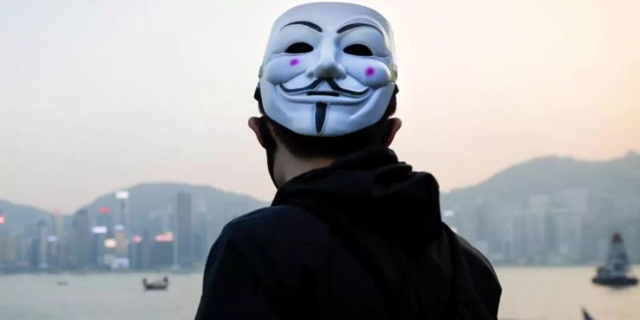 Ein prodemokratischer Demonstrant mit Guy-Fawkes-Maske beobachtet eine Kundgebung in Hongkong. Foto: Vincent Thian/AP/dpa