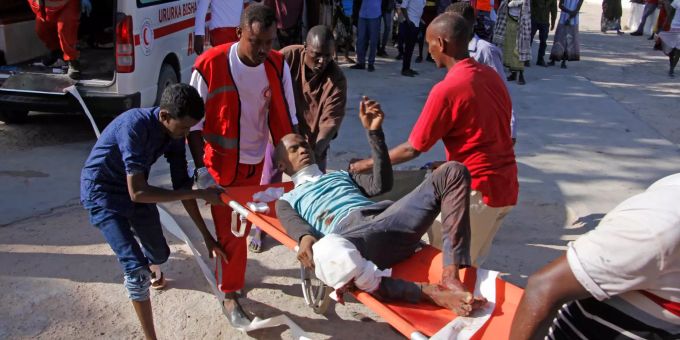Medizinisches Personal trägt einen Zivilisten, der bei einem Autobombenanschlag an einem Kontrollpunkt verwundet wurde. Explosion einer Autobombe in Mogadischu