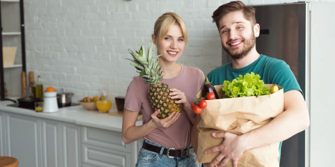 Mann und Frau mit Einkaufstüten voller Obst und Gemüse.