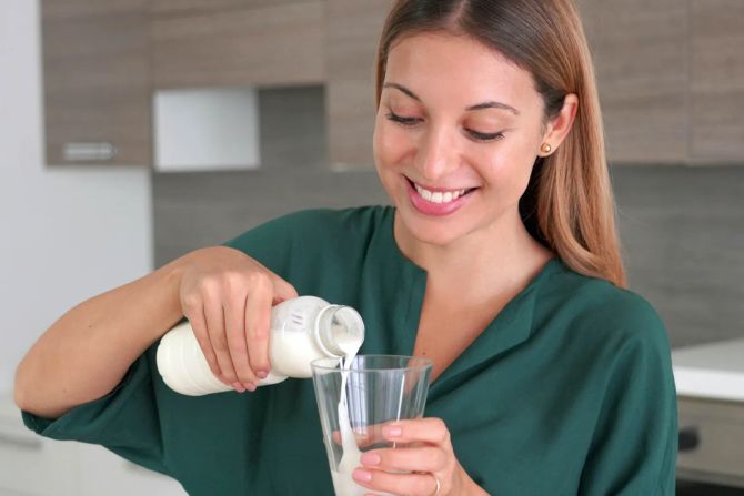 Junge Frau schenkt Milchgetränk ein