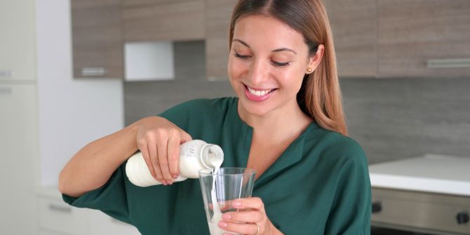 Junge Frau schenkt Milchgetränk ein